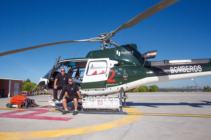 Paco Lucas (izda.) y Juan Cruz Nicolás junto al helicóptero de extinción de incendios que pilotan.